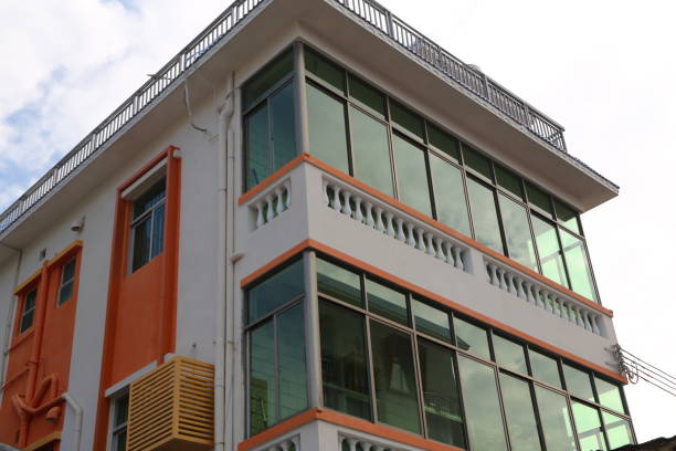 istock A three-story building with white walls and orange windows, featuring an iron railing on the roof terrace 2192789886