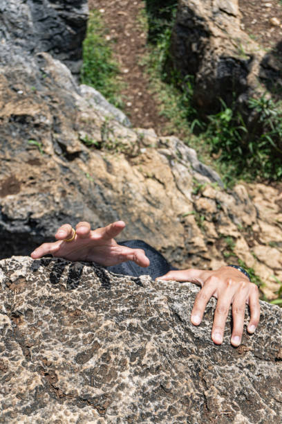 istock Hands grasp onto a rough rock face, hinting at climbing or exploration in a rocky terrain. 2192790700