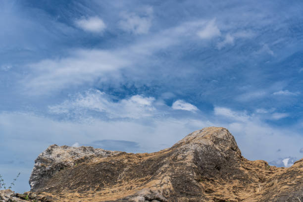 istock A rocky outcrop sits beneath a blue sky with wispy clouds, showcasing natural textures and colors. 2192790965