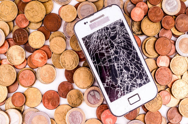 istock A broken cell phone is surrounded by a pile of coins 2192794248