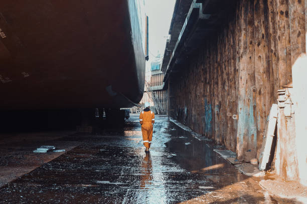 istock Worker walking at the bottom of the dry dock, with ship inside. 2192797691