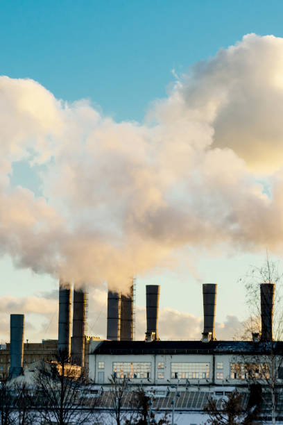 Industrial smoking chimneys against clear sunset sky. Concept of air pollution, ecology, environmental problems