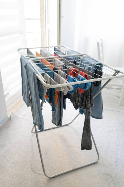 istock Laundry drying on an indoor clothes rack, with various garments including jeans and shirts 2192802188