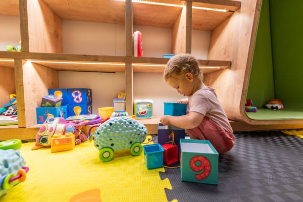 istock Toddler stacking colorful blocks and playing with toys in a bright learning playroom 2192802284