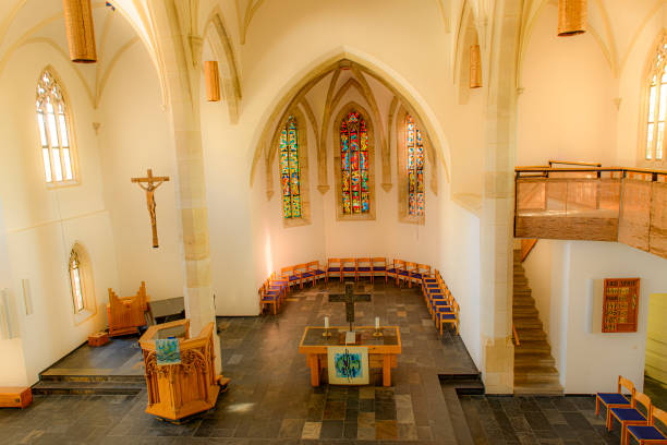 Church interior with a pleasant atmosphere. The renovated interior of the church with its white walls is bright and inviting. The light coming in through the windows is softly reflected and enhances the simple beauty of the room. And the black natural stone tiles reinforce this impression.