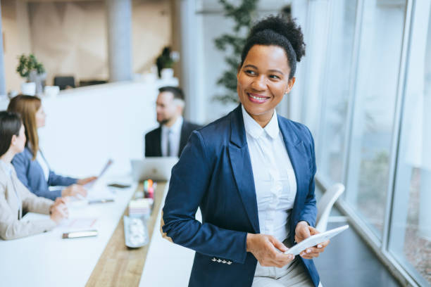 Positive woman holding tablet with team in background