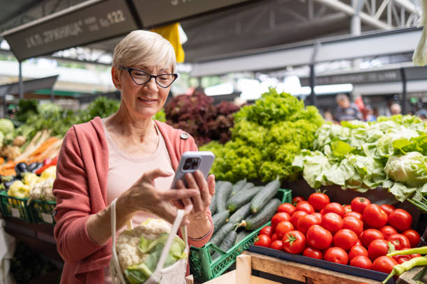 istock Smiling senior woman browsing phone at market 2192806889