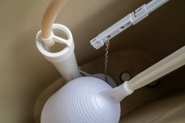 Interior of a toilet tank showing components like the fill valve, float assembly, and flush mechanism during maintenance work Various components are arranged in the tank of a toilet. The fill valve, float assembly, and flush mechanism are visible, indicating ongoing maintenance work. flushing valve public restroom toilet stock pictures, royalty-free photos & images