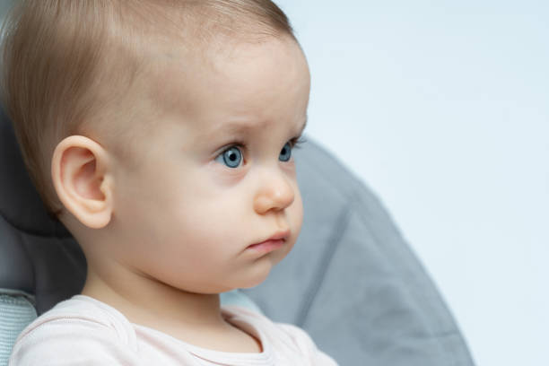 Thoughtful baby with bright blue eyes and a side profile