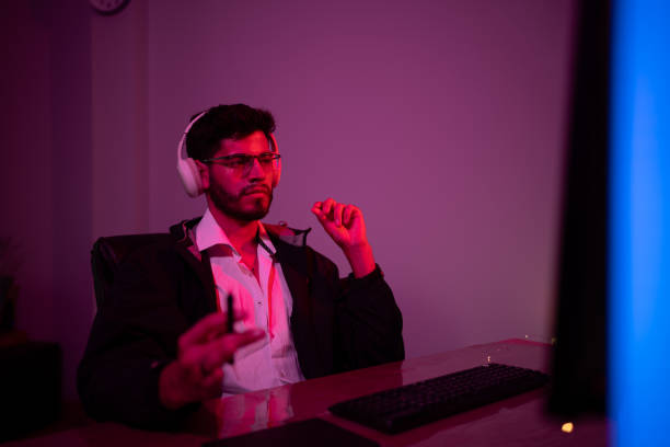 istock Young man engaged in tech activity with headphones in a dimly lit workspace during evening hours 2192813314