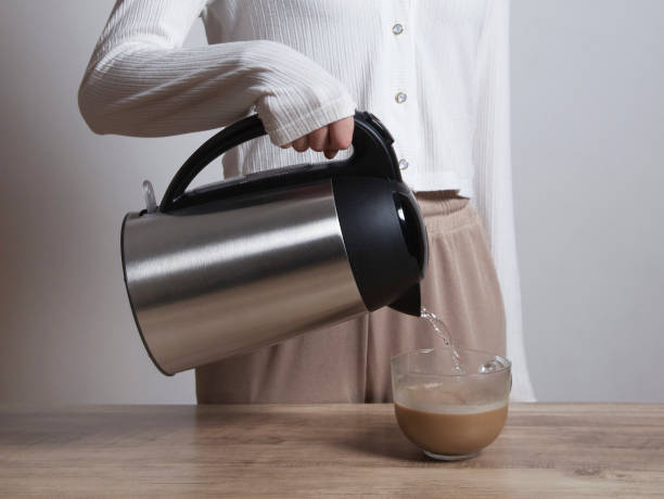 A woman pouring herself hot coffee into a mug