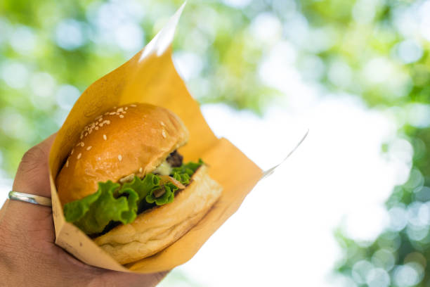 istock Hands holding pork burger in brown craft paper 2192821152