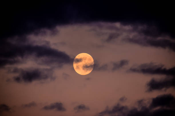 istock A large, glowing moon is visible in the sky, surrounded by dark clouds 2192830225
