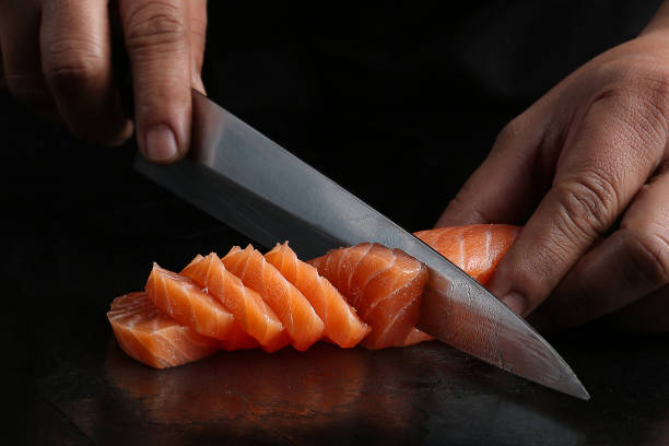 istock A chef slicing fresh salmon fillet with a sharp Japanese knife, showcasing precision and technique on a dark background. 2192833492