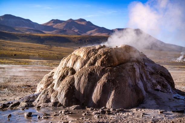 Natural geothermal activity captured in the Atacama Desert of Chile, showcasing steaming geological formations against a stunning mountainous backdrop.