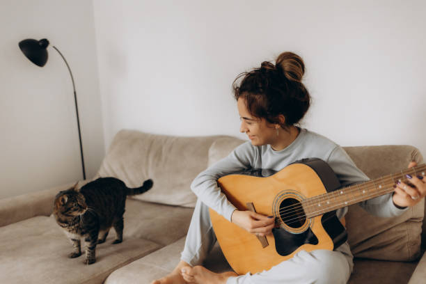 istock a woman plays guitar for a cat at home 2192839465
