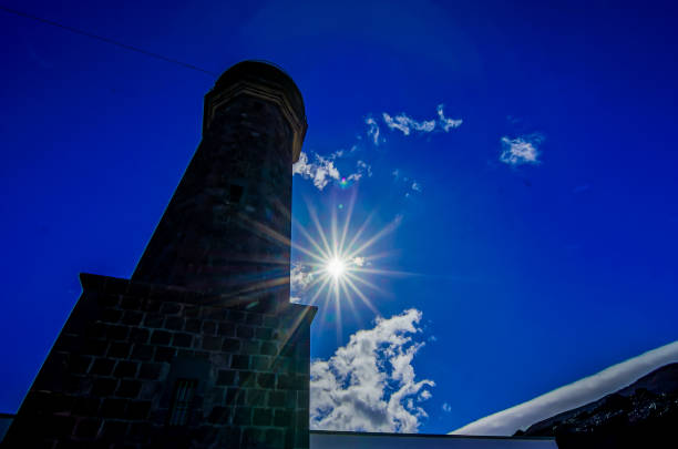 A tall tower with a sun shining on it. The sky is blue and clear