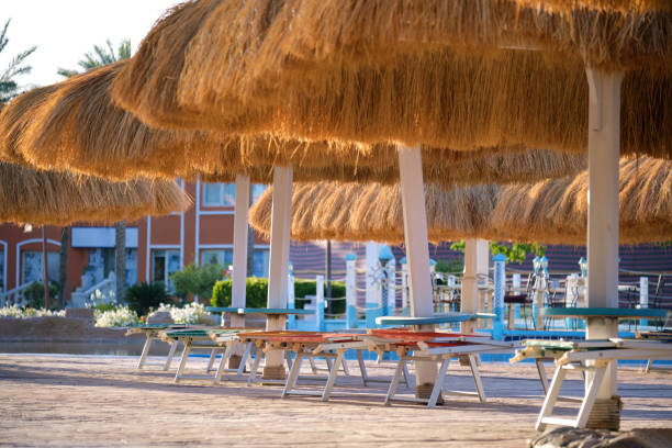 istock Empty deck chairs under straw shade umbrellas on swimming pool side in tropical resort. Summer vacations and getaway concept 2192844523