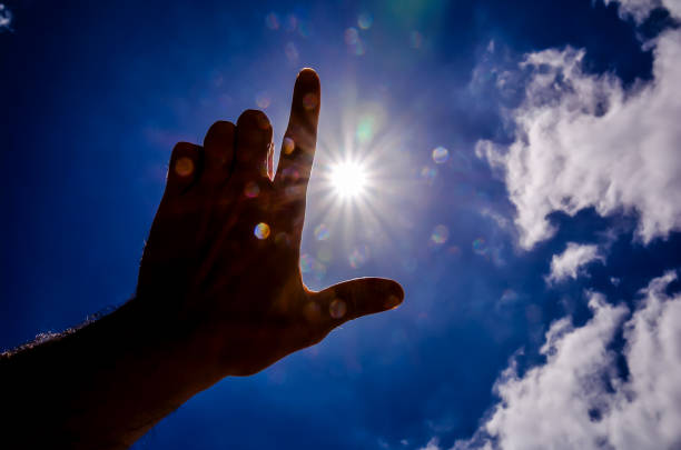 istock A hand is pointing to the sun, with the sun's rays shining through the clouds 2192844743