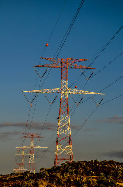 istock Two tall power lines with a white and red cross on top 2192844748