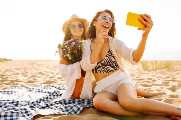 istock Two young beautiful smiling women on beach taking selfie. 2192849882