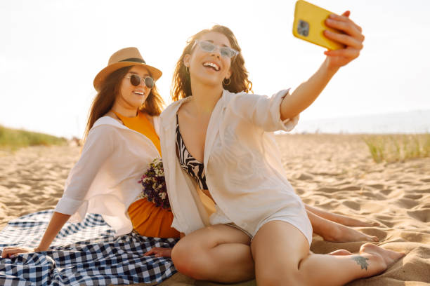 istock Two young beautiful smiling women on beach taking selfie. 2192849886