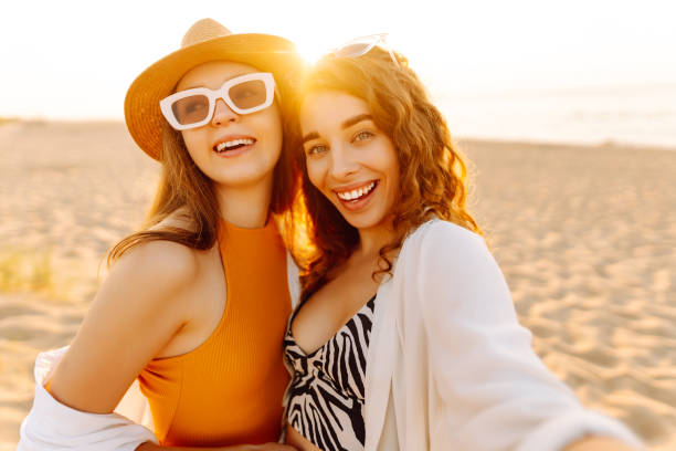 istock Two young beautiful smiling women on beach taking selfie. 2192849898