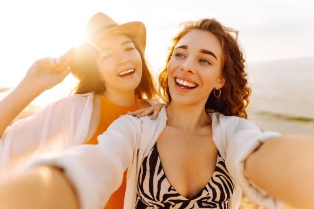 istock Two young beautiful smiling women on beach taking selfie. 2192849899
