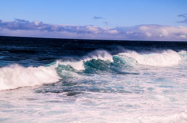 The ocean is calm and the sky is blue. The water is a deep blue color. The sky is clear and the sun is shining