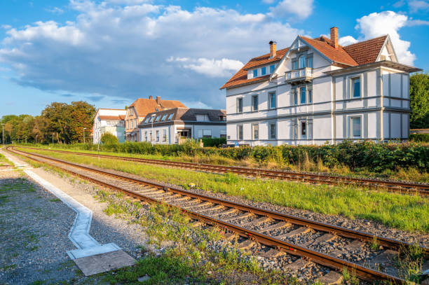 A scenic view of a railway track running alongside residential houses in Bad Mergentheim under a blue sky with clouds.