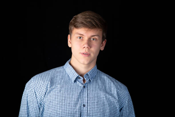 A young man in a blue shirt on a dark background