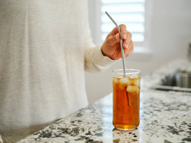 A woman putting a reusable drinking straw into a cold beverage.