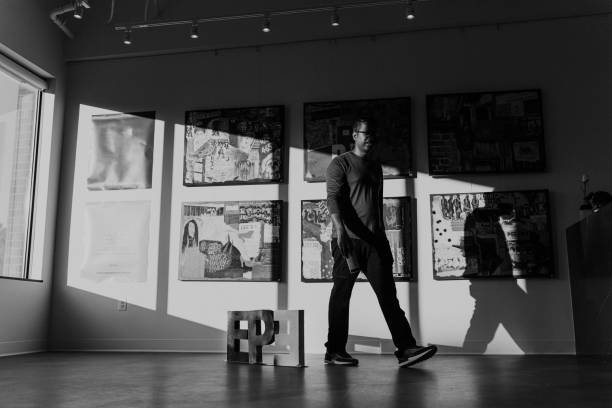 Man walking past art installation in medical office waiting room A male dentist of Indian descent walks past artwork he created and has on display in the waiting room of the dental clinic he owns. fine art image pictures stock pictures, royalty-free photos & images