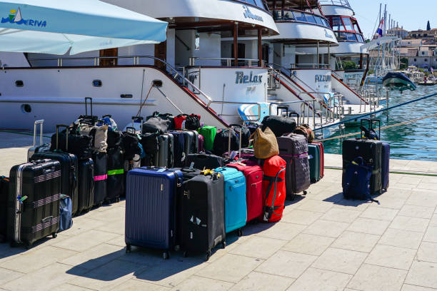 Trogir, Croatia - September 21, 2024: Big-sized luxury motor yachts moored at the Trogir promenade pier, many travel suitcases in the foreground.