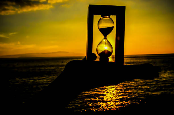istock A hand holding a sand timer on a beach at sunset 2192859518