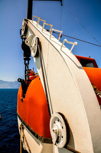 A boat with a red lifeboat on it. The boat is in the ocean and the lifeboat is attached to the boat