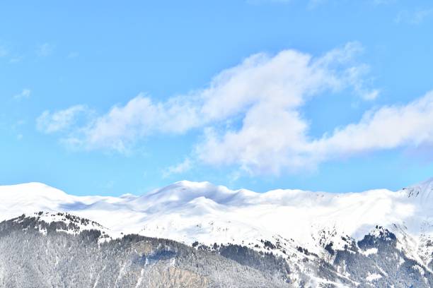 The image features a picturesque view of snow-capped mountains beneath a blue sky. Its minimalist composition emphasizes a harmonious color palette and simple forms. Perfect for a poster or artwork, it radiates tranquility and freshness, creating a sense of space and natural beauty. Ideal for interior design, it adds elegance and a relaxing atmosphere.