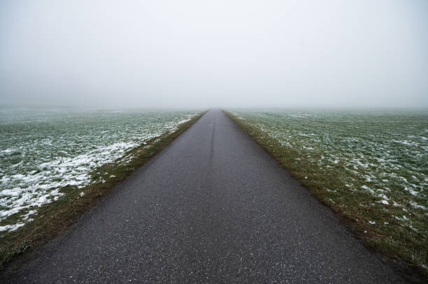 Mystical road in white fog stretching into the distance