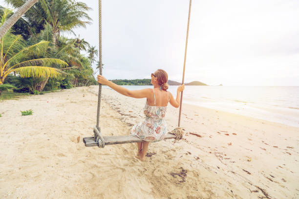 istock Woman Enjoying a Swing on Tropical Beach at Sunset 2192864454