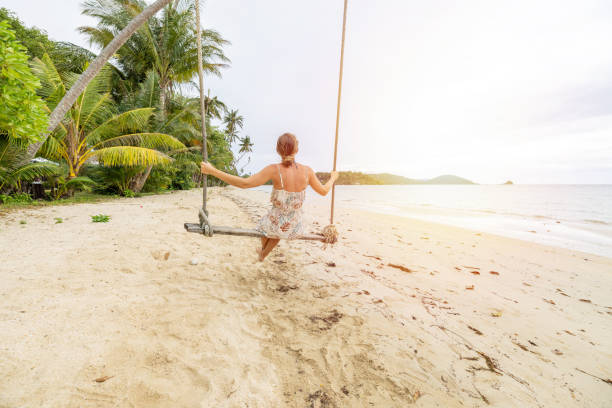 istock Woman Enjoying a Swing on Tropical Beach at Sunset 2192864456