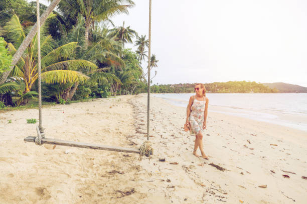 istock Woman Walking on Tropical Beach Near Palm Trees 2192865312