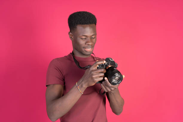 istock Young man checking photos on his mirrorless camera with a pink background 2192870942