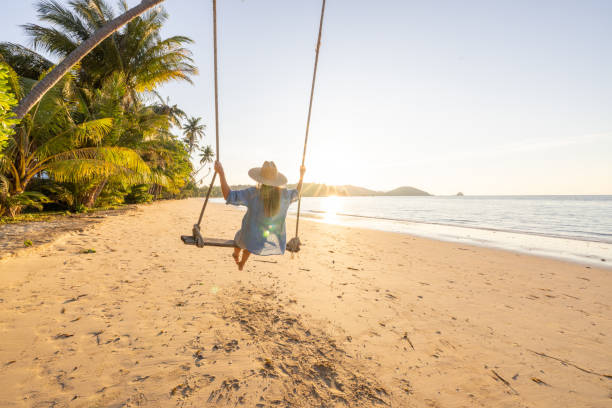 istock Woman Enjoying a Beach Swing Under Palm Trees 2192870998