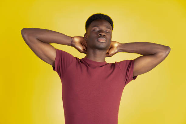 istock Young man relaxing with hands behind head on yellow background 2192871001
