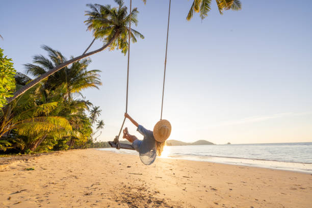istock Woman Enjoying a Beach Swing Under Palm Trees 2192871016