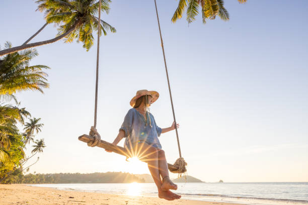 istock Happy woman at sunset playing on a swing on the beach 2192871151