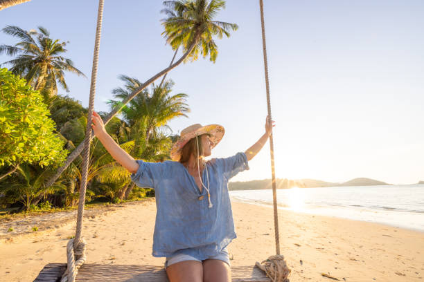 istock Woman Enjoying a Swing on a Tropical Beach at Sunset 2192871153