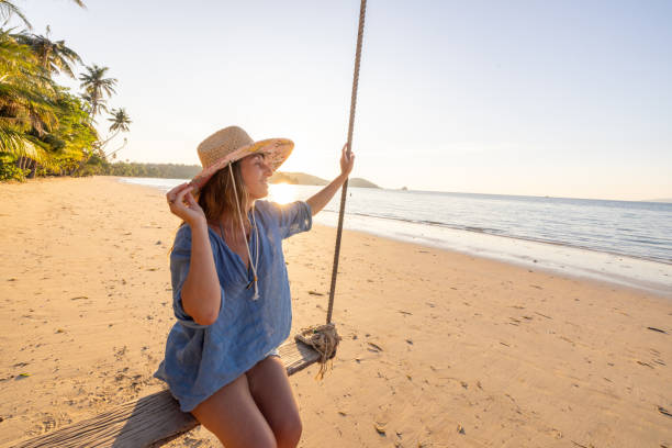 istock Happy woman at sunset playing on a swing on the beach 2192871242