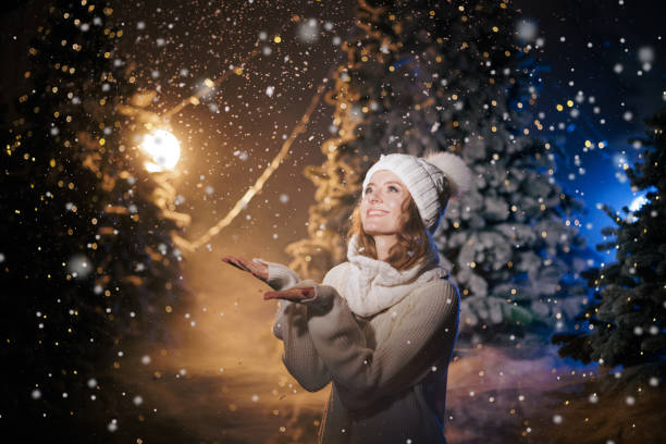 istock Woman Enjoying Snowy Night in Illuminated Forest 2192871246