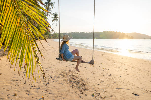 istock Woman on Beach Swing Enjoys Tropical Sunset 2192871569